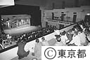 畳を敷いた二階席より芝居を見る観客