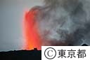 火口から火山灰を噴き上げる三原山、左は火口展望台